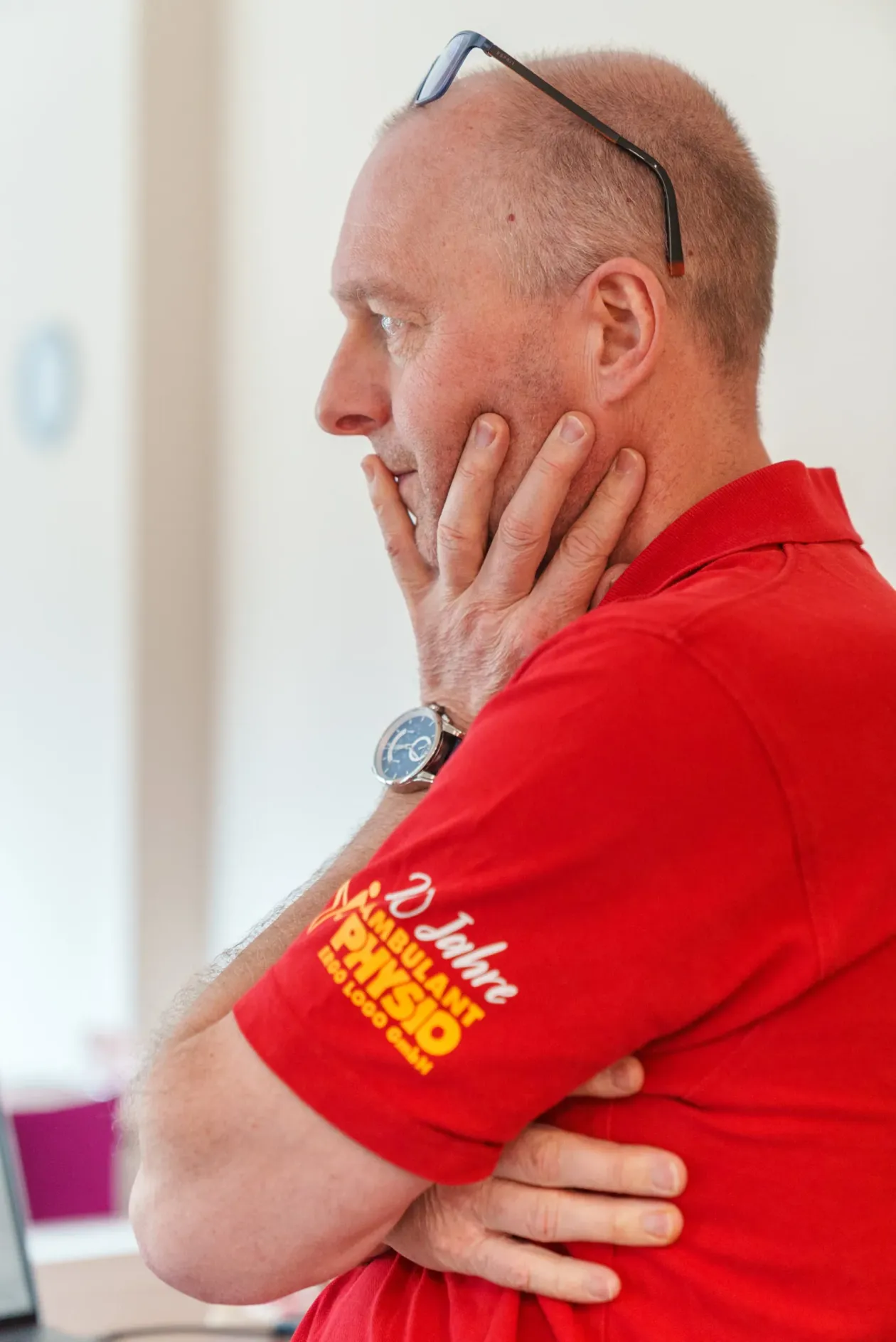 Torsten „TOHO“ Erler im roten Poloshirt, nachdenklich mit der Hand am Kinn, im hellen Büro